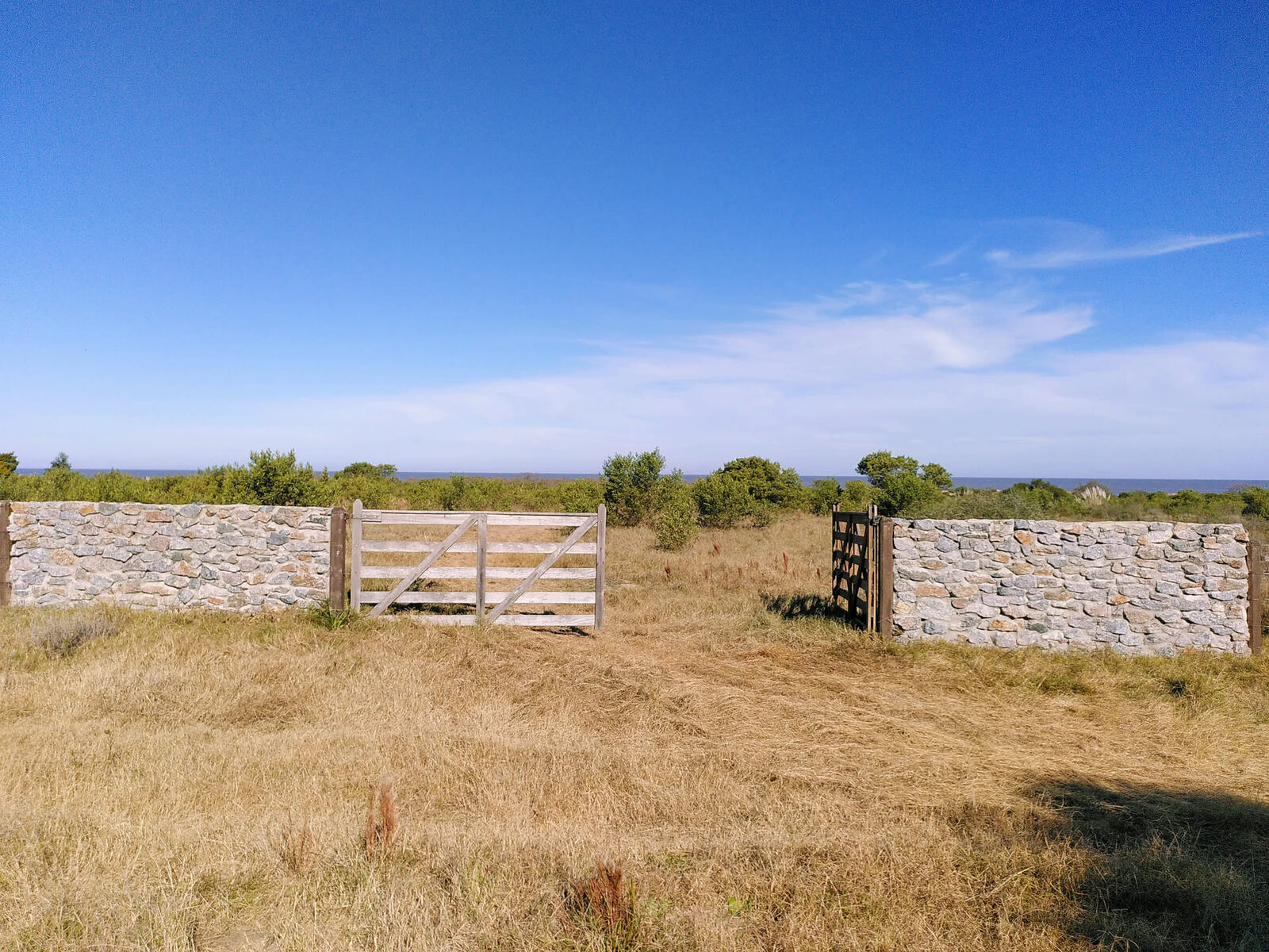 Steinmauer und Holztor am Grundstückszugang